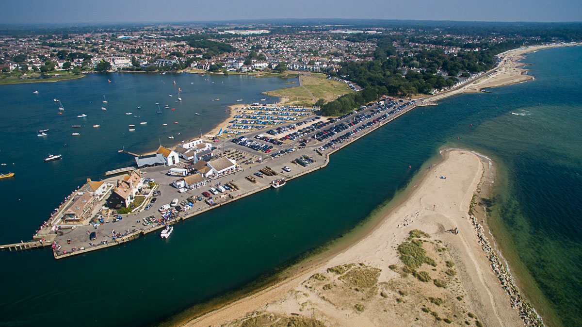 A beautiful aerial view of Mudeford Quay on a warm day, featuring families crabbing